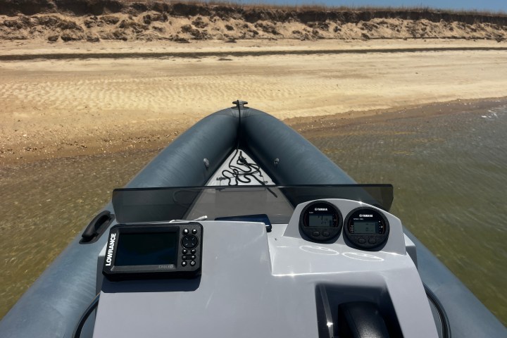 Small inflatable boat on sandy shore with navigational equipment.