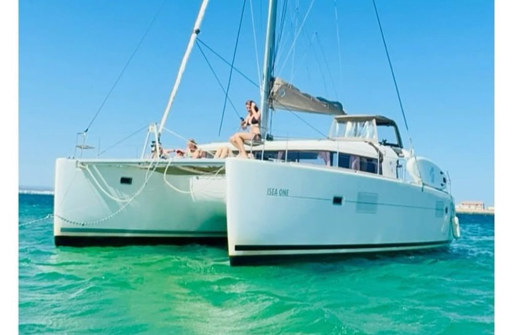 A catamaran sailboat on clear turquoise water under a bright blue sky.